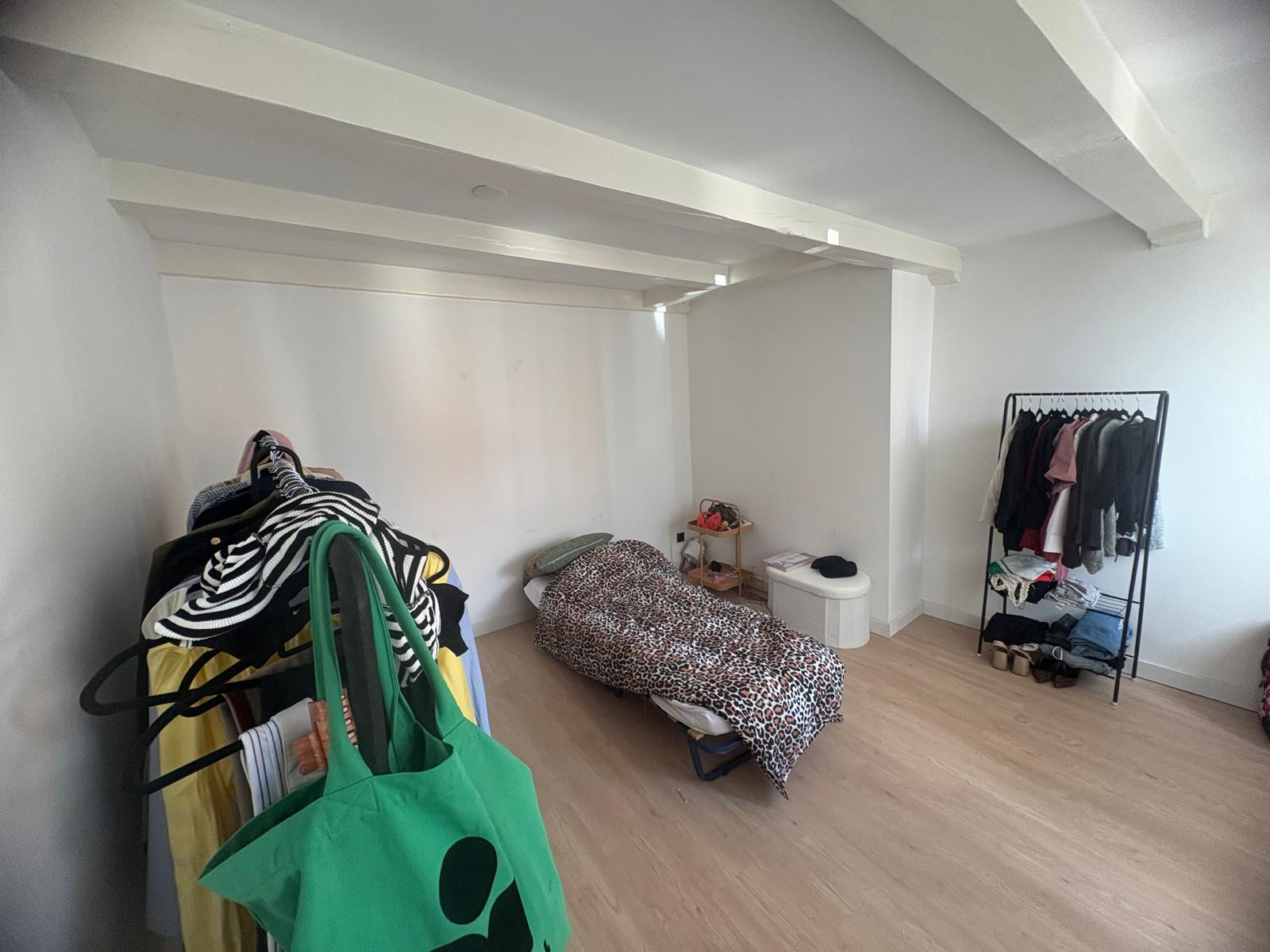 Bedroom with exposed ceiling beams and light wood flooring